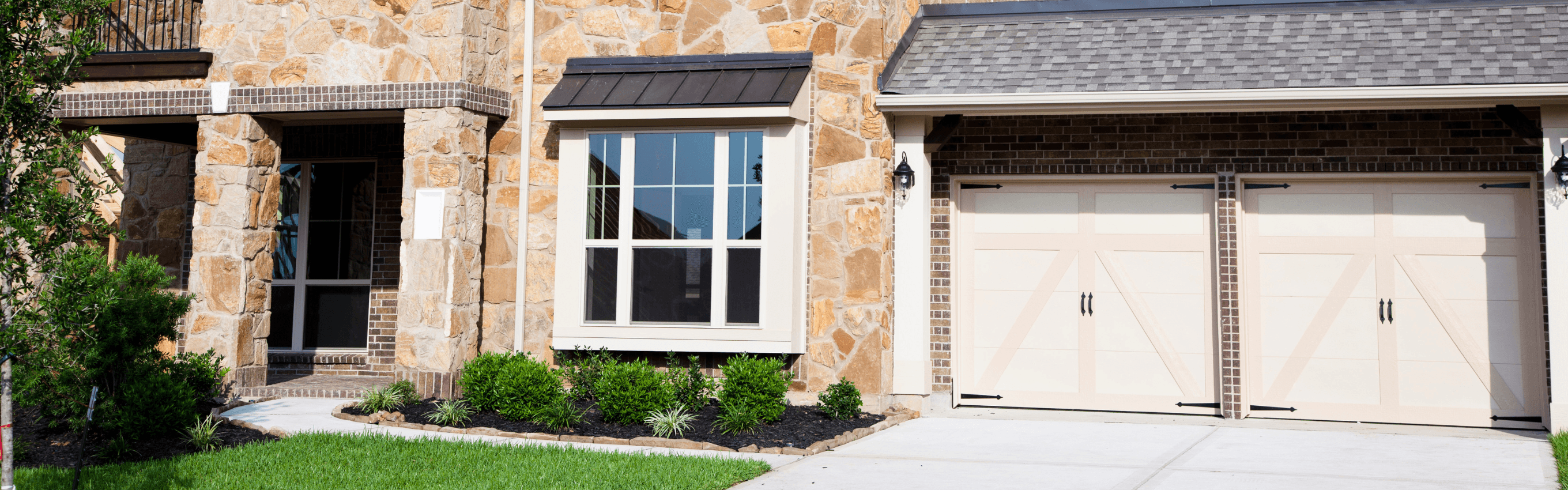 Exterior view of a three-level split home with stone and brick accents, large windows, and a double garage—representing modern residential architecture.