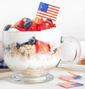Red, White, And Blueberry Homemade Ice Cream An Independence Day Special image 8 red white and blue parfait in glass dish with American flag fresh strawberries and blueberries frosted fusions