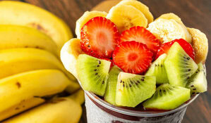 Can I Give My Baby Ice Cream image 5 pot of fresh chopped fruits banana strawbs kiwi with a hand of bananas in the background frosted fusions