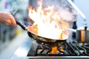 Homemade-Baked-Alaska-Its-the-Bomb-image-9-flames-coming-from-frying-pan-over-a-hob-where-flambeing-is-taking-place-fork-frosted-fusions
