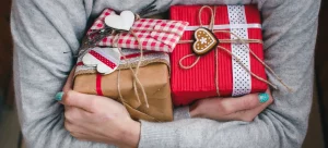 Frau hält liebevoll verpackte Weihnachtsgeschenke im Arm – eine Erinnerung, dass Weihnachtsstress oft von überzogenen Erwartungen an Geschenke kommt.