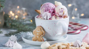 12-irresistible-christmas-ice-cream-recipes-for-your-holiday-table-image-2-scoops-of-ice-cream-in-a-white-bowl-with-gingerbread-men-and-cnady-canes-and-festive-decor-frosted-fusions