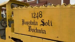 Yellow industrial vehicle with the black text "1248 Kopalnia Soli Bochnia" on its side, referencing the historic Bochnia Salt Mine&mdash;one of Poland&rsquo;s oldest; a must-see from any travel guide for unique visiting tips.