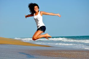 femme qui saute avec le sourire sur une plage