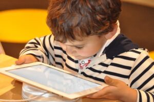 Petit garçon qui tient une tablette numérique entre ses mains.