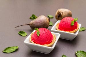 Homemade-Beetroot-Ice-Cream-Naturally-Sweet-Vibrant-image-5-scoops-of-fresh-beetroot-ice-cream-in-white-dishes-with-2-raw-beetroot-and-fresh-green-leaves-scattered-frosted-fusions