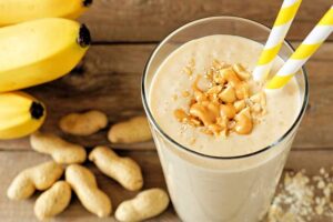 Quick-Easy-And-Deliciously-Healthy-Breakfast-Smoothie-Recipes-image-4-peanut-butter-and-banana-smoothie-with-fresh-banana-and-fresh-peanuts-to-the-side-Frosted-Fusions