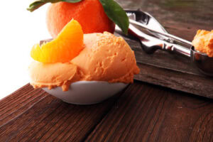 Celebrating-Chinese-New-Year-With-Lucky-Ice-Cream-Flavours-image-3-mandarin-ice-cream-with-fresh-mandarin-segment-and-ice-cream-scoop-Frosted-Fusions