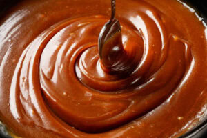 Homemade Humbug ice cream recipe image 4 close up of thick dark toffee sauce with silver spoon Frosted Fusions
