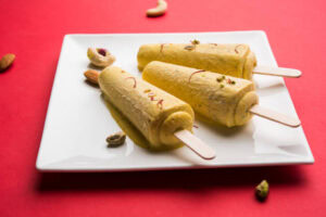 Rich-Creamy-Delicious-Homemade-Kulfi-Ice-Cream-A-Taste-Of-India-image-3-Kulfi-ice-cream-on-white-plate-with-chopped-nuts-to-garnish-Frosted-Fusions