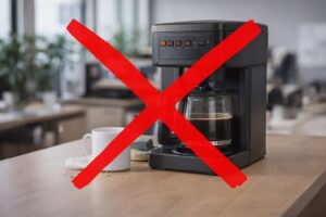 Old office coffee machine in workplace kitchen with a red X through it.