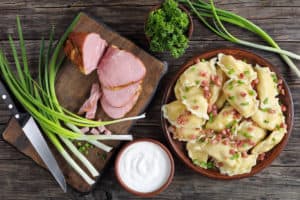 A plate of dumplings with ham and onions, showcasing the best Polish food, on a wooden table.