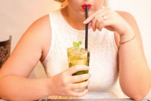 A woman savors a refreshing drink through a straw.