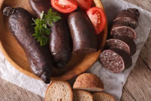 Weird Polish sausages, tomatoes and bread arranged on a wooden plate.