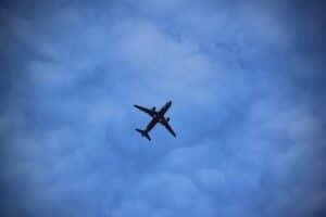 A commercial airplane is flying overhead against a blue sky with scattered clouds.