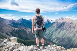 Homme en train de randonner avec un sac sur le dos, dans un paysage de montagne