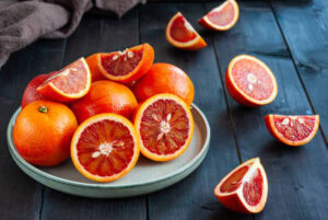 Learn-How-To-Make-The-Perfect-Blood-Orange-Sorbet-image-3-blood-oranges-on-a-plate-some-sliced-in-half-to-show-theinternal-colour-Frosted-Fusions