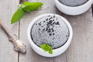 Celebrating-Chinese-New-Year-With-Lucky-Ice-Cream-Flavours-image-4-black-sesame-and-peanut-ice-cream-in-white-dish-with-fresh-green-leaves-and-silvery-spoon-Frosted-Fusions