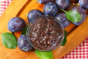 Powidlo Polish plum butter in a jar surrounded by plums.