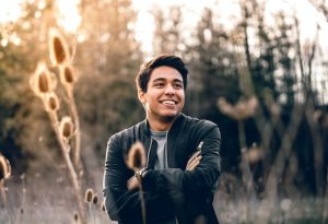 hispanic man standing in nature with arms crossed smiling