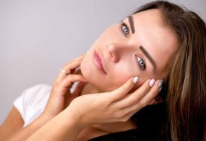 Jeune femme qui se touche la peau du visage