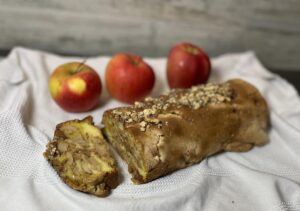 A loaf of Polish coffee cake roll with apples and nuts on a napkin.