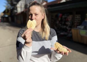 Woman holding traditional Polish cookies in a street market setting.