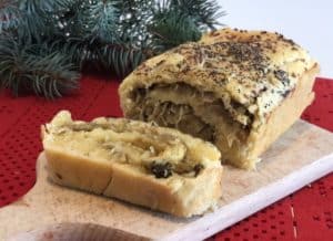 A loaf of bread is cut in half and sitting on a cutting board, awaiting the preparation of a Polish kulebiak recipe.