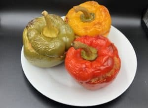 Polish Stuffed Peppers Recipe [Papryka Faszerowana] with three peppers on a white plate.