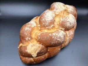 A braided bread, commonly found in Polish cuisine, showcased on a black surface.