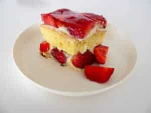 An authentic Polish Tort Truskawkowy, showcasing a slice of strawberry cake on a white plate.