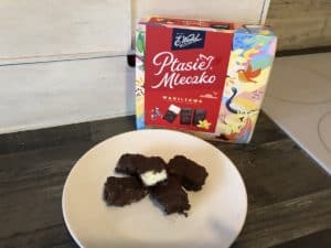 A plate of homemade chocolate Ptasie Mleczko on a table next to a box.