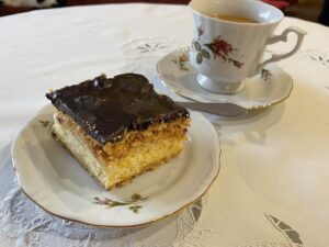 A delicious krolewiec Polish cake recipe on a plate with a cup of coffee.