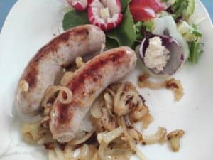 Authentic polish sausages and caramelized onions served on a plate, representing the exquisite flavors of Polish cuisine.