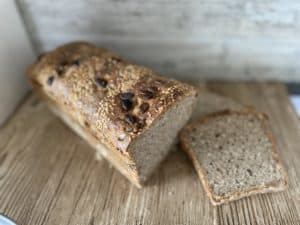 A slice of Polish multigrain bread on a wooden cutting board.