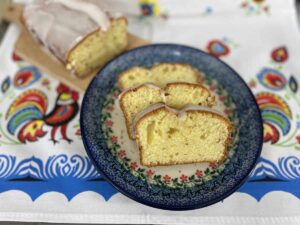 Sliced Polish cheese babka on a decorative plate with more cake in the background.