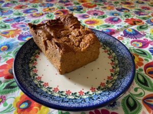 A slice of vegan pate topped with vegan pate is placed on a blue and white patterned plate, which is set on a colorful floral tablecloth.