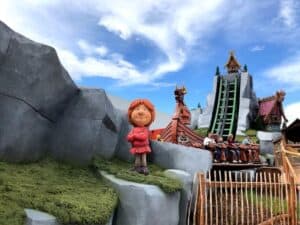 Outdoor amusement park ride with a Viking-themed statue in front, steep water slide in background, and riders descending in a log flume.