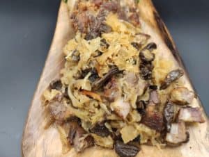 Bigos Myśliwski, a traditional Polish Hunter's Stew Recipe, featuring sauerkraut and meat on a wooden cutting board.