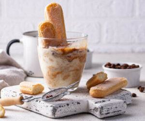 indulge-your-senses-with-a-decadent-tiramisu-ice-cream-recipe-image-4-glass-of-tiramisu-ice-cream-with-lady-fingers-sticking-out-and-coffee-beans-in-white-dish-frosted-fusions
