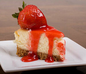 Homemade Strawberry Cheesecake Ice Cream Recipe image 1 slice of classic cheesecake with strawberries and strawberry sauce drizzled over it frosted fusions