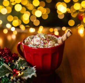 12-Irresistible-Christmas-Ice-Cream-Recipes-For-Your-Holiday-Table-image-6-large-red-cup-filled-with-ice-cream-and-waffle-straws-and-christmas-decor-and-lights-in-the-background-frosted-fusions