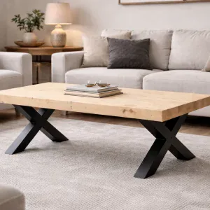 White spruce coffee table with thick three-plank top and black X-shaped legs in a relaxed modern living room