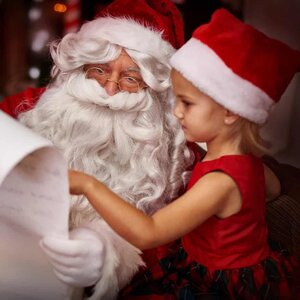 Santa Claus and a child in a red outfit, both members of the festive foodies club, look at a long wish list together.