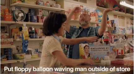 guy telling his wife how he's going to advertise by putting a big waving man outside