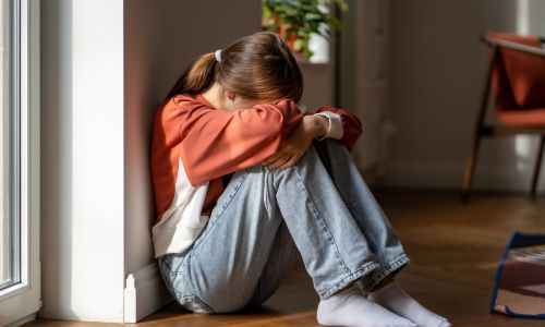 teenager sitting on the floor crying and having sign of depression