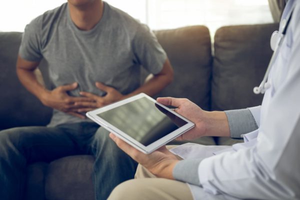 Two people. One is holding a tablet, the other is holding his stomach as if in pain.