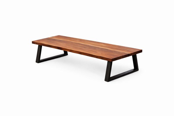 Solid walnut coffee table with narrow rectangular top and black metal legs