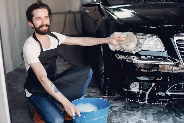 Man meticulously washes a sleek black car, showcasing dedication and pride in automotive care.