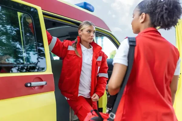 Paramedics prepare for action by the ambulance, showcasing teamwork and commitment to urgent care.